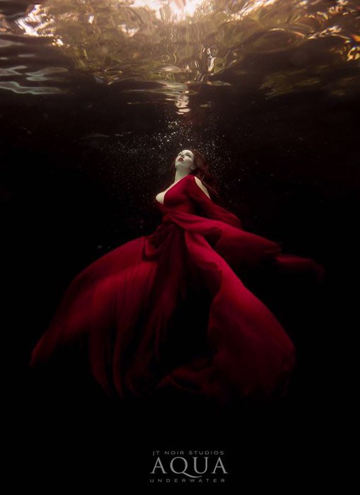 Атмосферная подводная фотосессия модели в красном платье, позирующей под водой