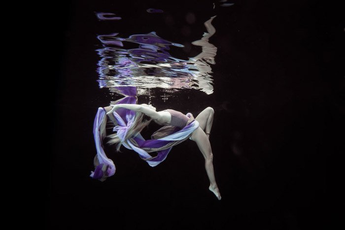 Атмосферная подводная фотосессия женщины-модели, позирующей под водой