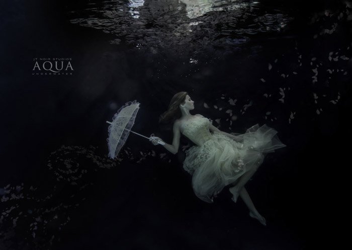 Атмосферная подводная фотосессия женщины-модели, держащей зонтик под водой