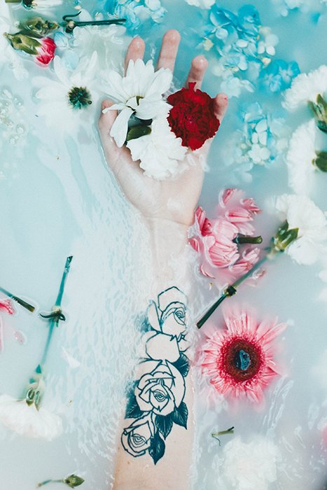 татуированная рука и цветы в молочной ванне