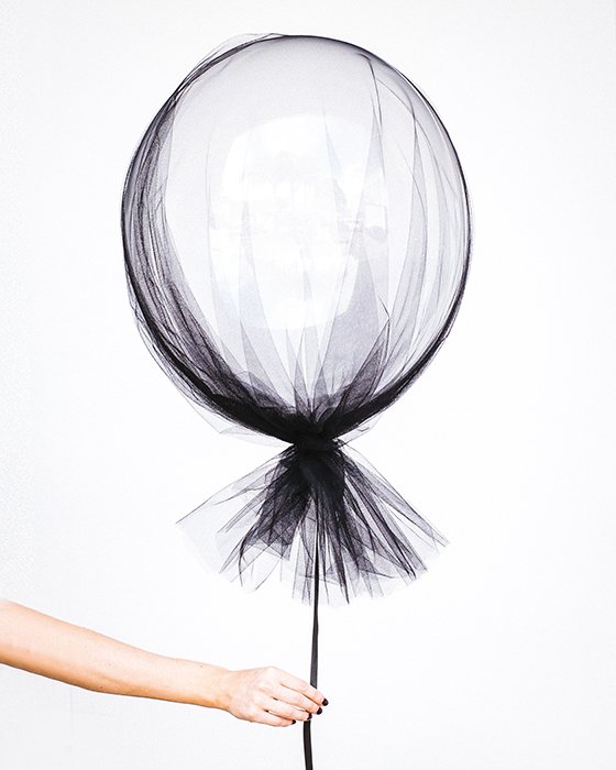 сюрреалистическая фотография руки, держащей обтянутый тканью воздушный шар