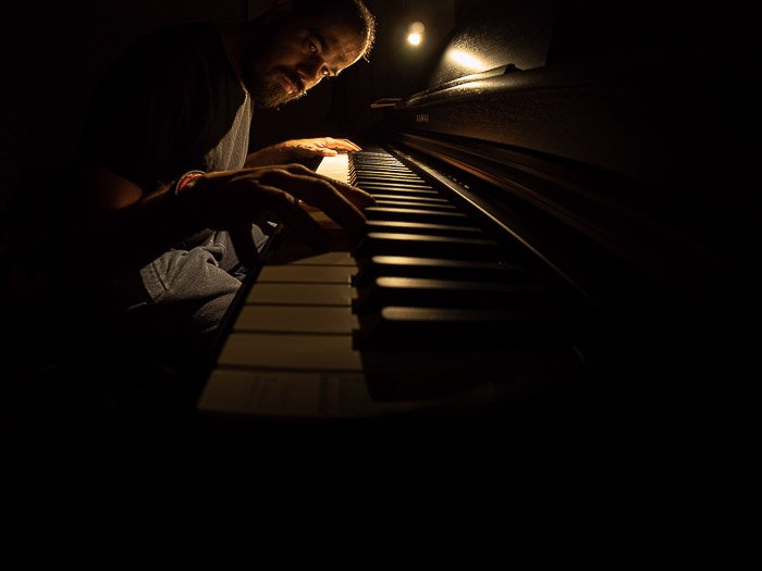 Атмосферное фото мужчины, играющего на пианино при слабом освещении