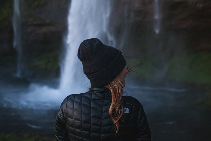 Женщина-фотограф перед водопадом в Исландии