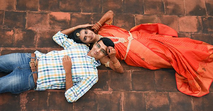Overhead shot of a wedding couple posing lying on the floor together - Indian wedding photography tips