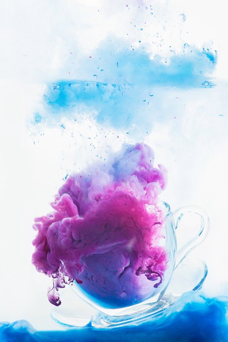 чашка, наполненная цветными облаками - красочные краски в воде фотография