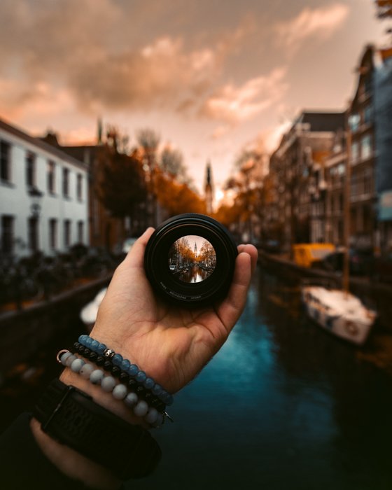 Креативная фотография человека, держащего объектив камеры перед камерой на Groenburgwal, Амстердам