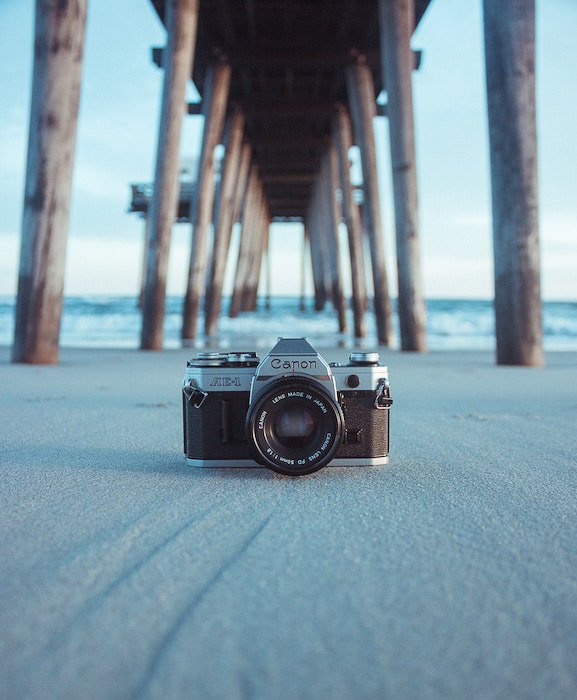 фотоаппарат canon film camera outdoors under the wooden pier