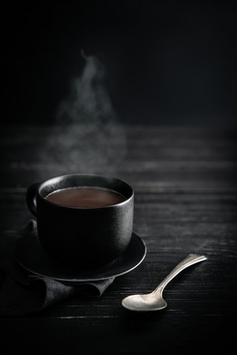 Стильная фотография чашки дымящегося кофе на темном фоне