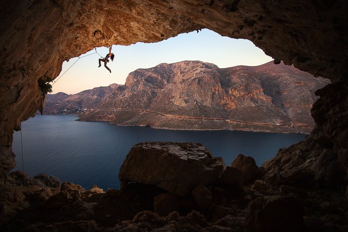 скалолаз над пещерой у воды и горного ландшафта - навыки приключенческой фотографии