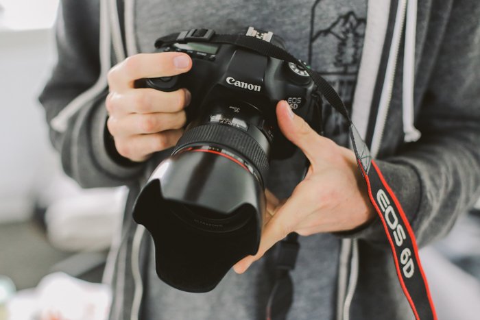 поиск руководств к фотоаппаратам онлайн: фотограф держит в руках canon dslr 