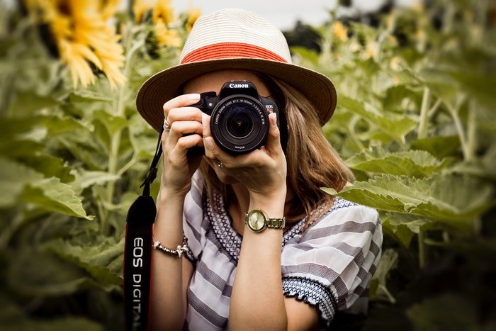 Женщина-фотограф наводит свой зеркальный фотоаппарат canon