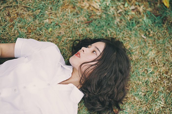 минималистский портрет женской модели, лежащей на траве