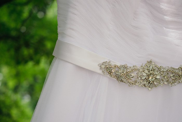 крупный план деталей свадебного платья на свадебной фотосессии на природе