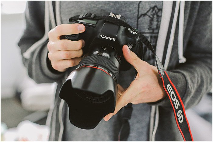 профессиональный портретный фотограф держит в руках зеркальный фотоаппарат canon - цены на портретную съемку