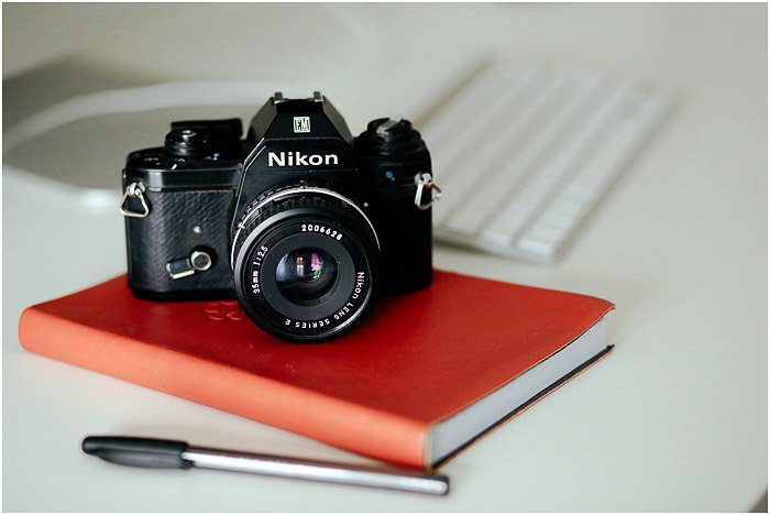 камера Nikon, лежащая на красном ноутбуке