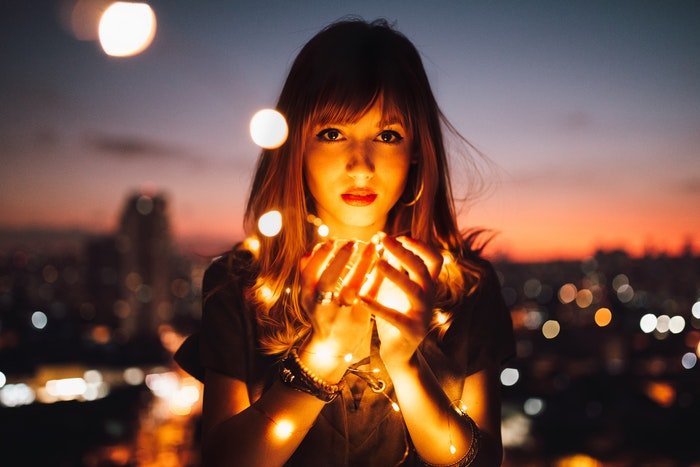 Девушка держит в руках фонарики, чтобы осветить свое лицо