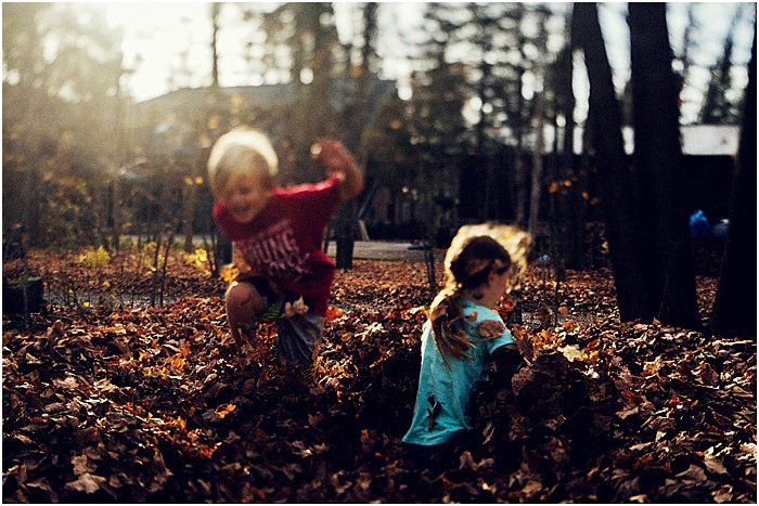 Фотография детей, играющих с осенними листьями
