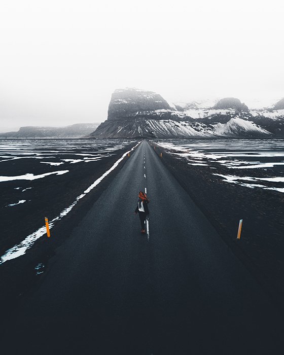 Фотография длинной дороги и заснеженных гор в мягком свете
