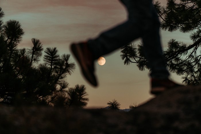 Фотография силуэта бегущего человека с луной на фоне