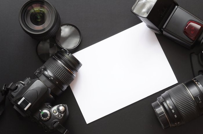 Фотография камеры, объективов и белого листа бумаги