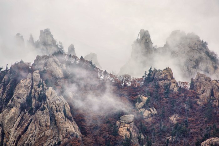 покрытые туманом горы, снятые с полным зумом на 300-мм объектив полнокадровой зеркальной камеры.