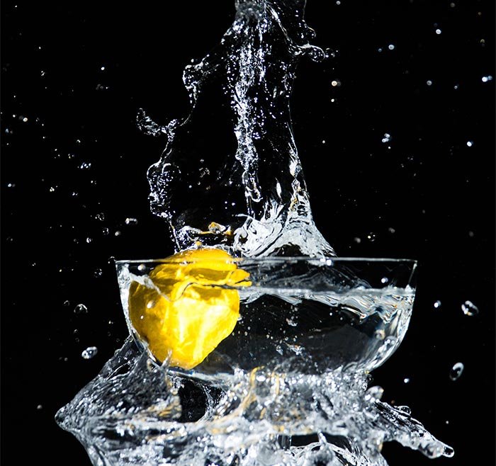 Фотография лимона, опущенного в миску с водой, что вызывает всплеск