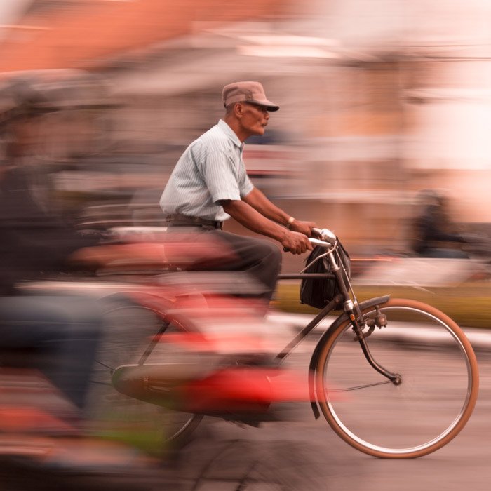 Фотография пожилого мужчины на велосипеде с эффектом размытия движения