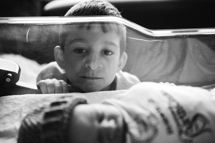 Фотография ребенка, наблюдающего за братом, спящим в кроватке