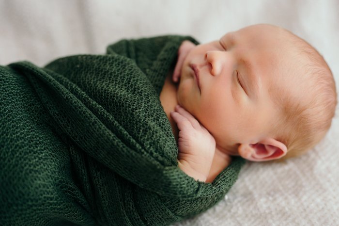Фотография крупным планом новорожденного ребенка, пеленаемого в одеяло