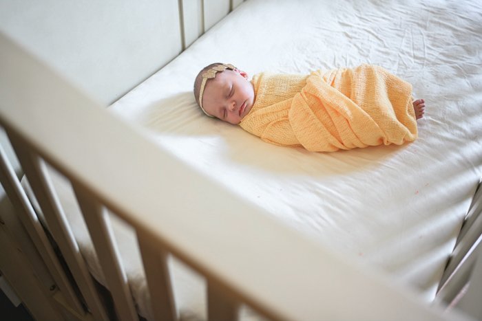Фотография младенца, спящего в желтом одеяле