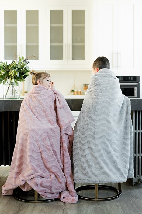 Два маленьких ребенка сидят на кухне, завернувшись в одеяла