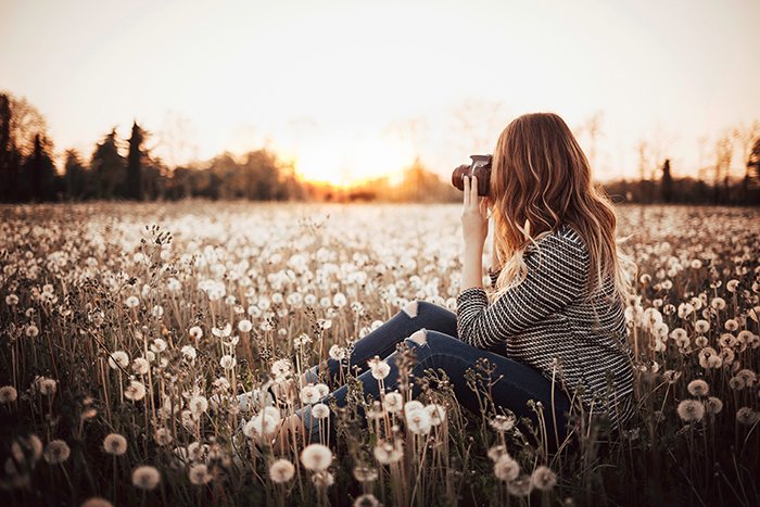 Девушка в поле фотографирует пейзаж