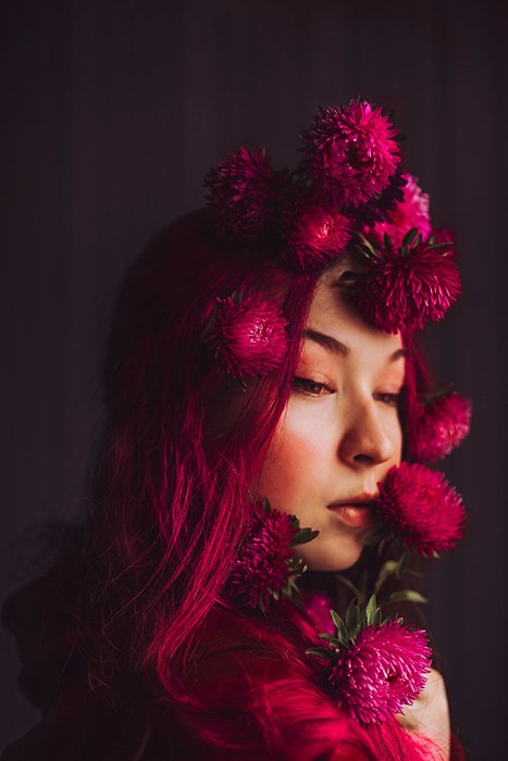 Портретная фотография женщины с розовыми цветами в волосах