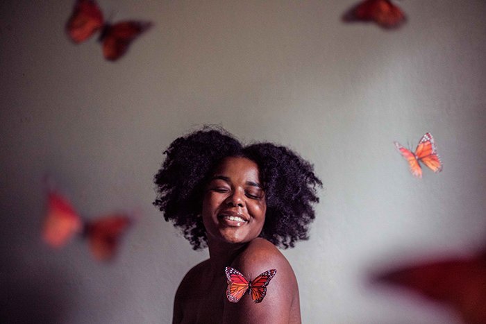Портретная фотография женщины с бабочками вокруг нее