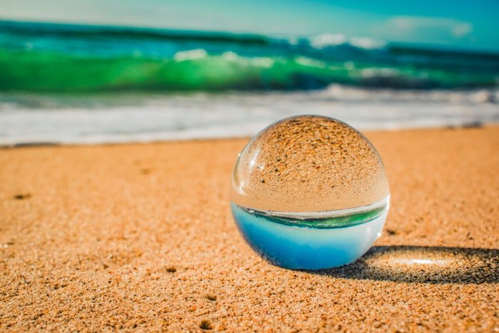 хрустальный шар лежит на песке пляжа, изображение отражается внутри