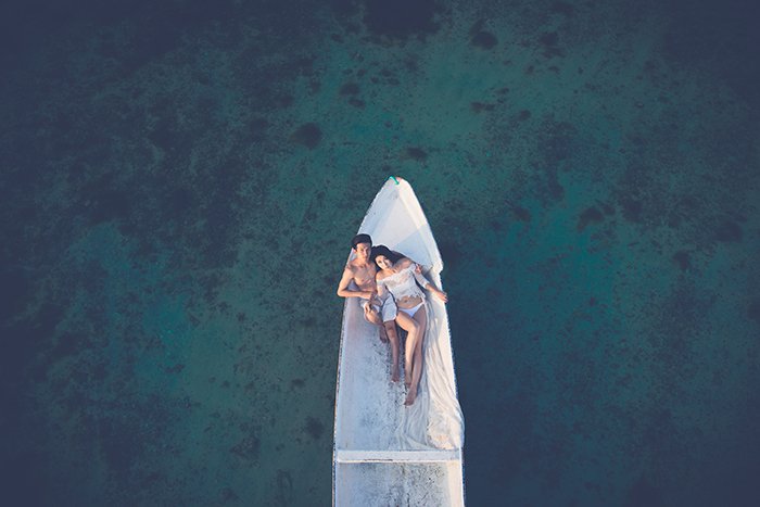 Свадебное фото с дрона с парой в лодке на море
