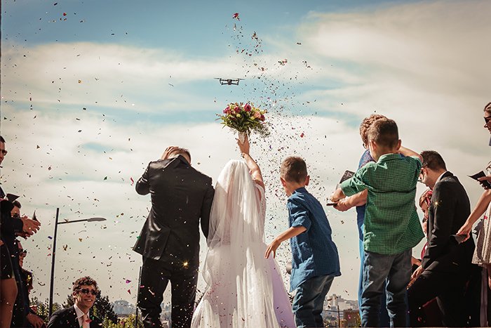 Свадебная фотография супружеской пары и лепестки цветов в воздухе