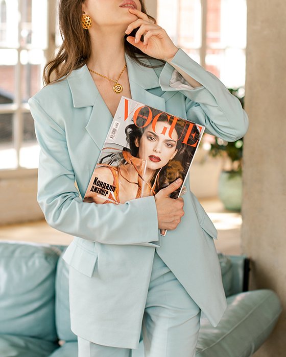 Фотография женщины в синем костюме, держащей журнал Vogue