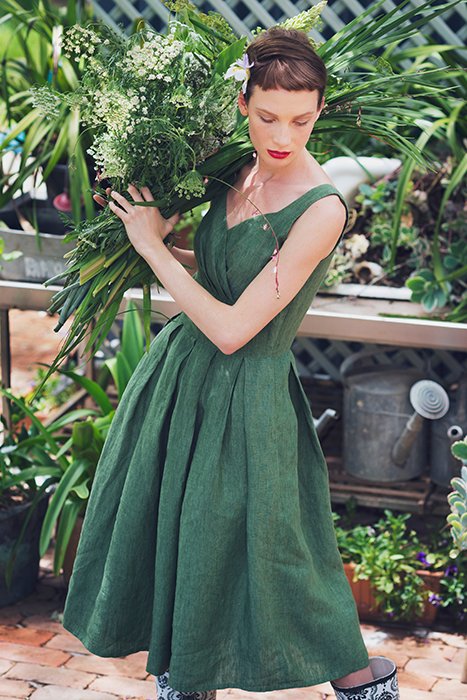 Фотография модели, одетой в зеленое, держащей растения