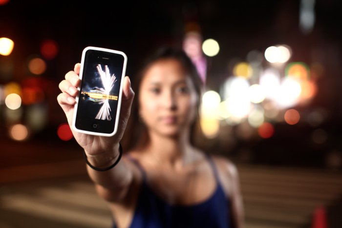 девушка держит iPhone на улице ночью