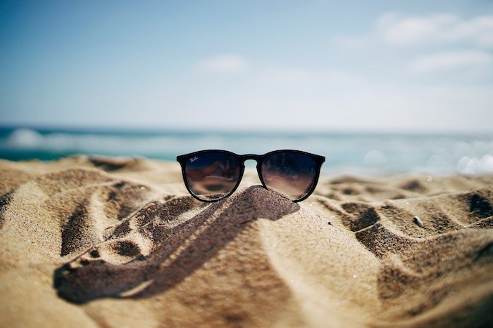 Фотография солнечных очков, сделанная на пляже на песке