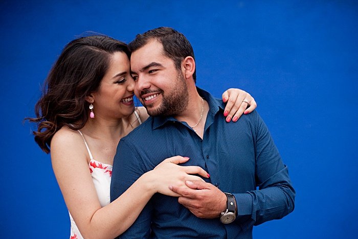 романтический портрет пары, пробующей позы для фотографии помолвки на синем фоне