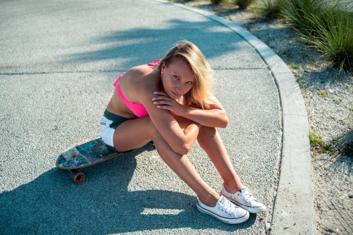 открытый портрет женской модели, сидящей на скейтборде