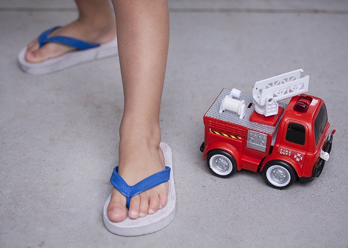 крупный план детских ног рядом с игрушечным грузовиком