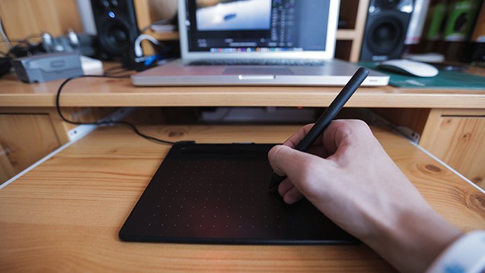 Крупный план рук человека, использующего стилус и блокнот с ноутбуком