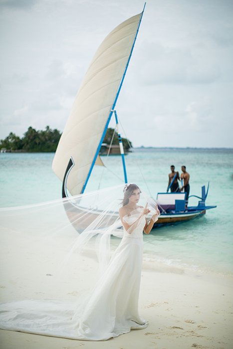Невеста позирует с лодкой на заднем плане