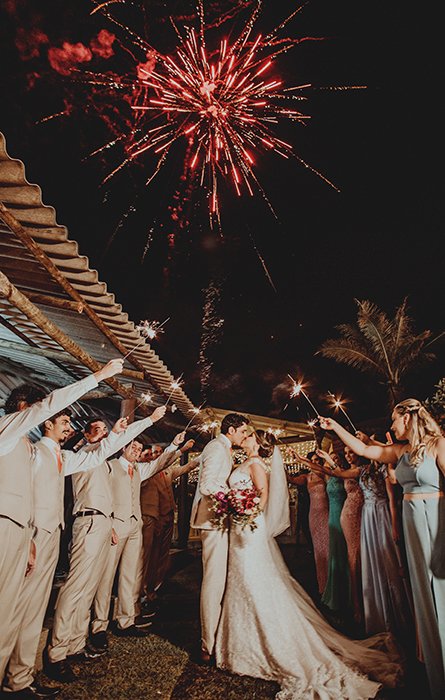 A bride and groom kissing surrounded by sparklers 