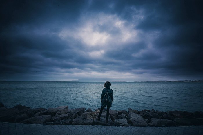 Человек стоит перед озером с темным небом