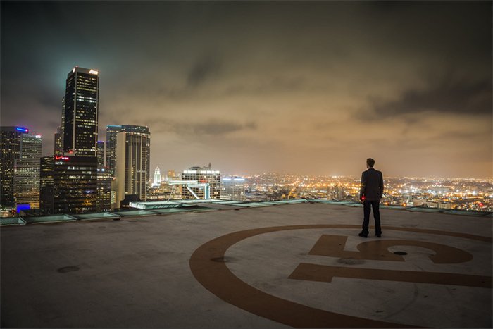 Мужчина стоит на крыше здания на фоне городского горизонта
