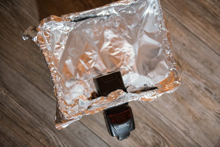 Вспышка, вставленная в крышку картонной коробки, покрытой фольгой